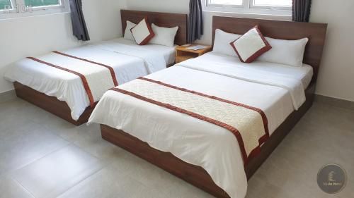 two beds sitting next to each other in a room at Vy An Hotel in Bao Loc