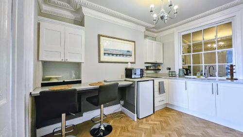 a kitchen with white cabinets and a table and chairs at INNit Joy in Brighton & Hove
