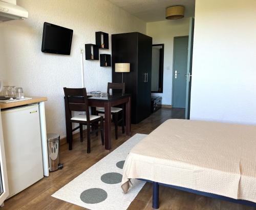 Cette chambre comprend un lit, une table et une cuisine. dans l'établissement SAINT-FLORENT Résidence piscine Studio 2 personnes FLO300-261, à Saint-Florent