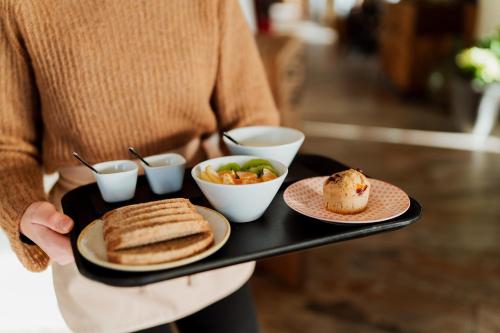 een persoon die een dienblad vasthoudt met ontbijtproducten erop bij Polisena L'Altro Agriturismo Veg in Pontida