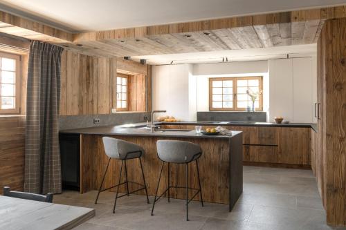 une cuisine avec un îlot et des tabourets de bar dans l'établissement Chalet Remy - Chalet de luxe - Montagnes de Saint Gervais, à Saint-Gervais-les-Bains