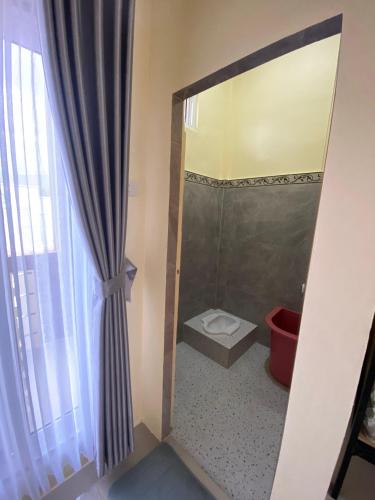 a bathroom with a shower with a toilet and a mirror at Ben And Ethan Rooms in Balige
