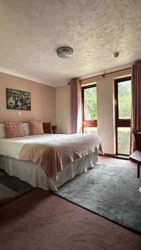 a bedroom with a large bed and two windows at Farmhouse Inn in Thaxted