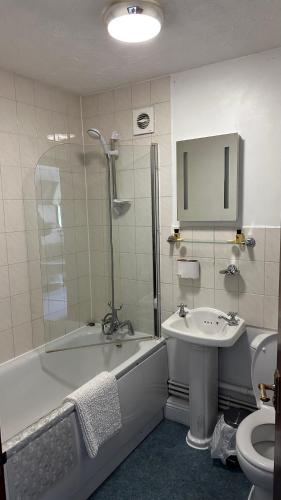 a bathroom with a sink and a tub and a toilet at Farmhouse Inn in Thaxted