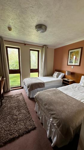 a hotel room with two beds and two windows at Farmhouse Inn in Thaxted