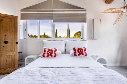 une chambre avec un grand lit blanc avec des oreillers rouges dans l'établissement Secret d'Uzès - Le Duché - Piscine chauffée et Jacuzzi, à Uzès