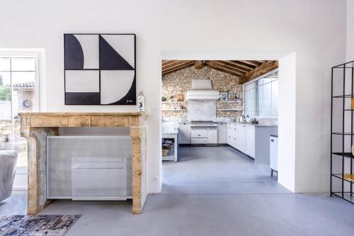 une cuisine avec des placards blancs et un mur en briques dans l'établissement Secret d'Uzès - Le Duché - Piscine chauffée et Jacuzzi, à Uzès