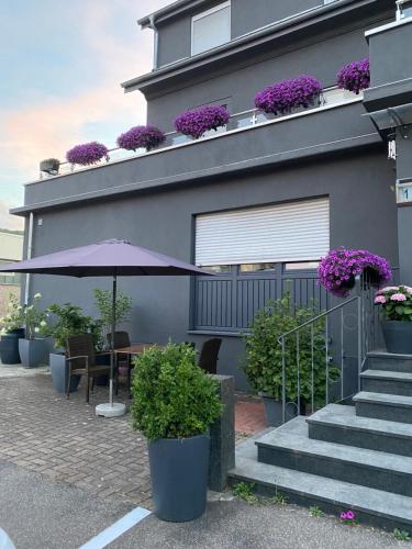 a building with a table and an umbrella and flowers at 1 grosse elegante Zimmerwohnung 5 Minuten zu Fuss in die Stadtmitte in Lörrach