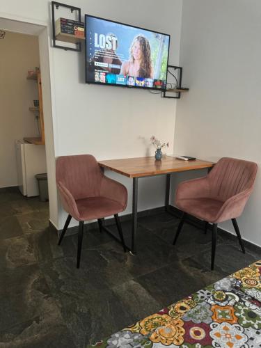 a room with a table and two chairs and a tv at Bellas apartmani in Novi Sad