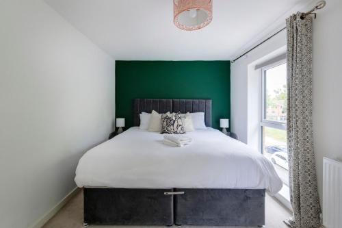 a bedroom with a large bed with a green wall at Gorgeous 4-bed Home in Nottingham by Renzo, Free Driveway Parking, Great Location! in Nottingham