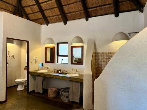 a bathroom with two sinks and two mirrors at Nyati Safari Lodge in Hoedspruit