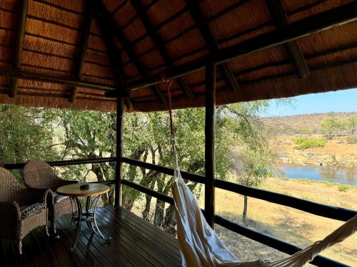 a porch with a hammock and a view of a river at Nyati Safari Lodge in Hoedspruit