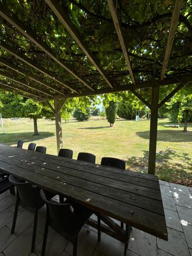 a wooden table and chairs under a pavilion in a park at Closerie 3 étoiles La Poire à Loup, Domaine avec Piscine in Vaulandry