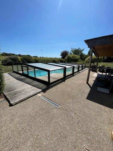a swimming pool with a table and a wooden deck at Closerie 3 étoiles La Poire à Loup, Domaine avec Piscine in Vaulandry