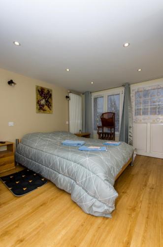 un grand lit dans une chambre avec un plancher en bois dans l'établissement A 1Okm des plages du débarquement, Chez Sabrina, gîte entre mer et campagne, proximité Caen, Bayeux, Arromanches, aéroport Carpiquet, à Lantheuil