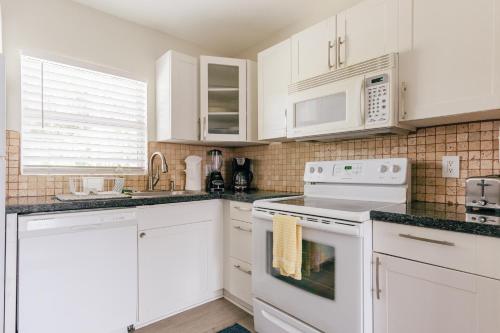 a white kitchen with white cabinets and white appliances at Secluded Beach Adventure Cabana - Newly Renovated! in Pompano Beach