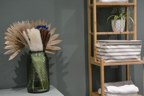 a green vase with flowers in it next to a shelf at Bel appartement neuf proche de Paris in Maisons-Laffitte