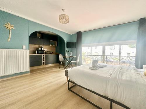 a bedroom with a large bed and a kitchen at Flamingo Vibes, central et élégant in Limoges