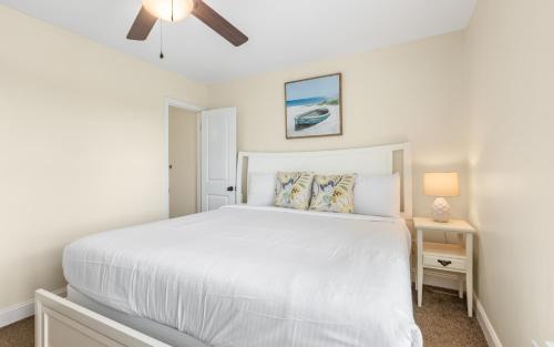 a bedroom with a white bed and a ceiling fan at Seaclusion by Oversee 30A in Inlet Beach