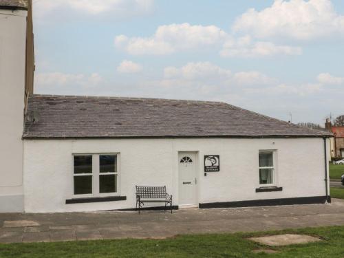 a white building with a bench in front of it at Salmon Cottage in Berwick-Upon-Tweed