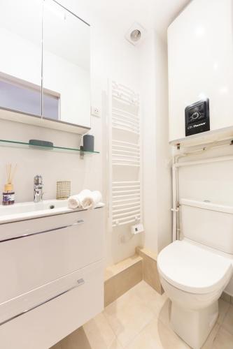 une salle de bain blanche avec des toilettes et un lavabo dans l'établissement T2 petit nid rose, à Ivry-sur-Seine