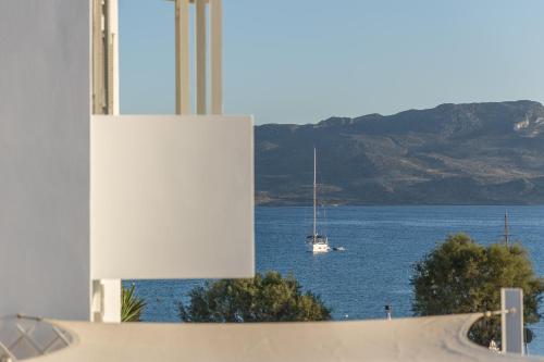 a sailboat on the water with a boat in the ocean at Ostria Hotel  in Adamas