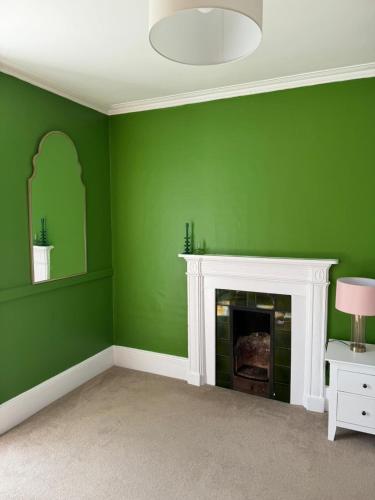 a green room with a fireplace and a mirror at Pilgrims Rest in Chichester