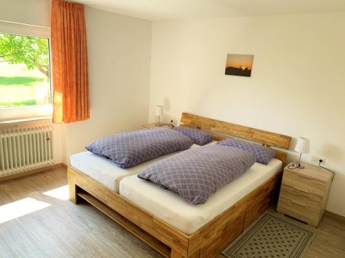 a bedroom with a bed with purple pillows and a window at Gästehaus Erika in Tengen