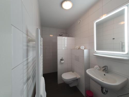 a white bathroom with a toilet and a sink at 'n Ice Day 3A in Zoutelande