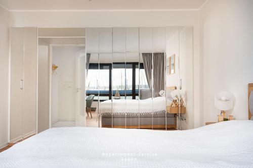 a bedroom with a white bed and a large mirror at FeWo Hafenkino in Laboe
