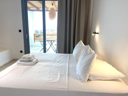 a bedroom with a bed with white sheets and pillows at Spanos Apartments in Agios Petros