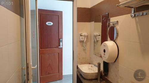 a bathroom with a door and a sink and a toilet at Vy An Hotel in Bao Loc