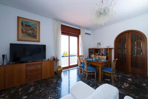 Una sala de estar con una mesa y un televisor. en Skyview Paradise House, en Amalfi