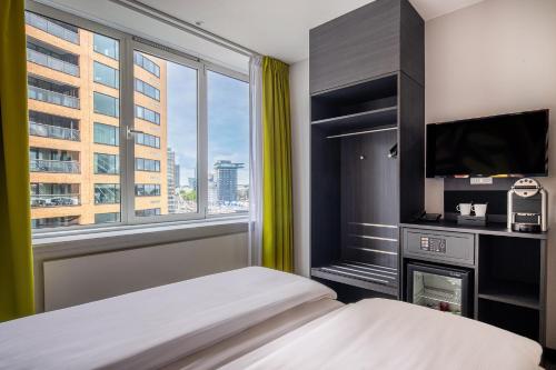 a bedroom with a bed and a tv and a window at Thon Hotel Rotterdam City Centre in Rotterdam