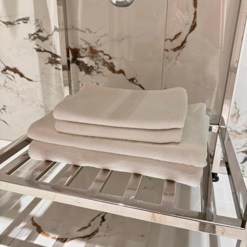 a stack of white towels on a shelf in a bathroom at SV Hotel, Restaurant & Airport Parking in Todoreshty