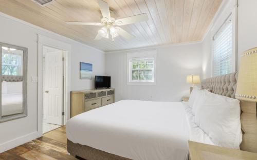 a white bedroom with a bed and a ceiling fan at Shores Fun by Oversee 30A in Seacrest