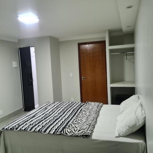 a bedroom with a zebra print bed with a wooden door at Nasser Hotel Aeroporto in Núcleo Bandeirante