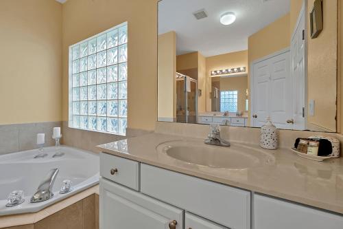 a bathroom with a sink and a large mirror at Entire home w/ Private Pool,Gated Near Disney in Orlando