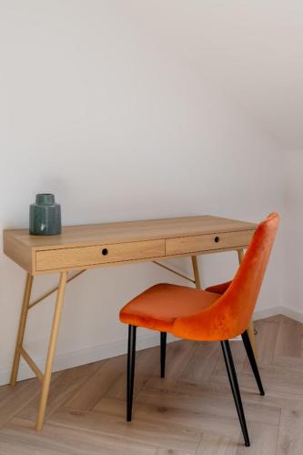 a wooden desk with a orange chair next to it at APARTAMENT KWIATKA parking klimatyzacja in Płock