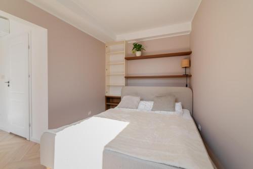 a white bedroom with a bed and shelves at APARTAMENT KWIATKA parking klimatyzacja in Płock