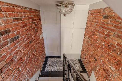 a brick wall and staircase with a chandelier at APARTAMENT KWIATKA parking klimatyzacja in Płock
