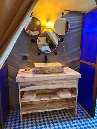 a bathroom with a sink and mirrors on the wall at Aladdin merzouga camp in Merzouga