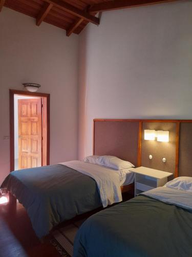 a bedroom with two beds and a door with a window at Bamboo Village Place in Tumbaco