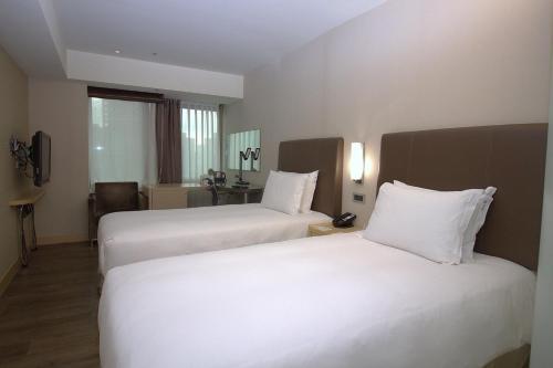 a hotel room with two beds with white sheets at Holiday Inn Express Taoyuan by IHG in Taoyuan