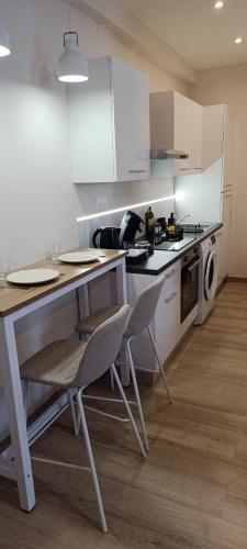 une cuisine avec des armoires blanches et une table et des chaises dans l'établissement Le Chic - Hyper Centre, à Charleville-Mézières