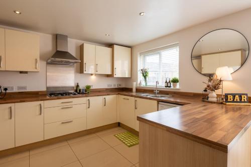 a kitchen with white cabinets and a large mirror at Cozy Glam Patchway Garden House Sleep 9 Mid-Long Term Welcome in Bristol