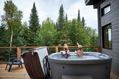 two children playing in a hot tub on a deck at Maison contemporaine Tremblant- Spa & tranquillité in Lac-Superieur