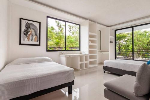 a bedroom with two beds and a couch and windows at CASA VS Casa nueva con alberca jacuzzi y jardín in Gallinero