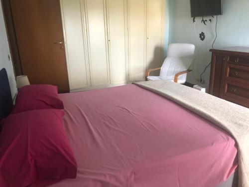 a bedroom with a pink bed with a chair at MomòHouse - 4 ospiti 2 camere WiFi A/C in Rome