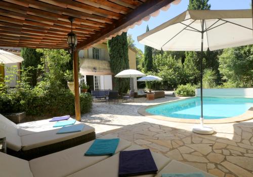 un patio avec un parasol et une piscine dans l'établissement Le clos de la tour cassis piscine chauffée, à Cassis